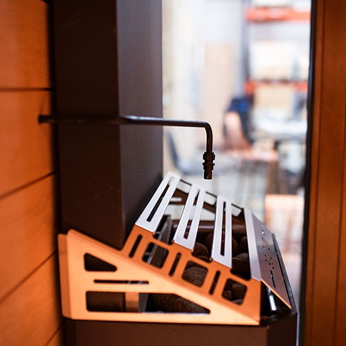 Close-up of the Saunum AutoLeil pipe and nozzle above the stones