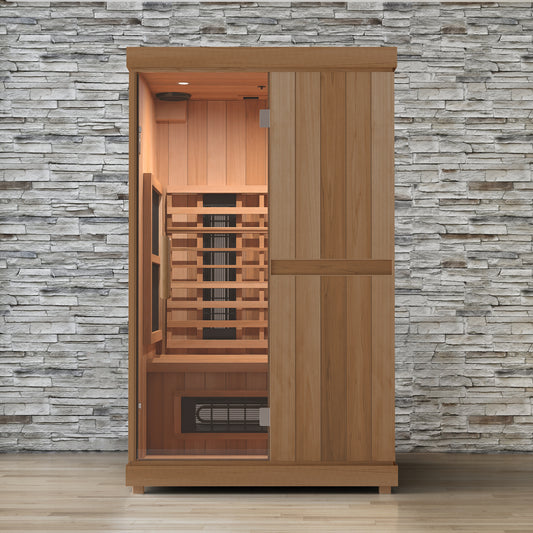 Finnmark FD-2 two person full spectrum infrared sauna lit against a stone wall, glass door on the left showing the cedar bench and infrared panels