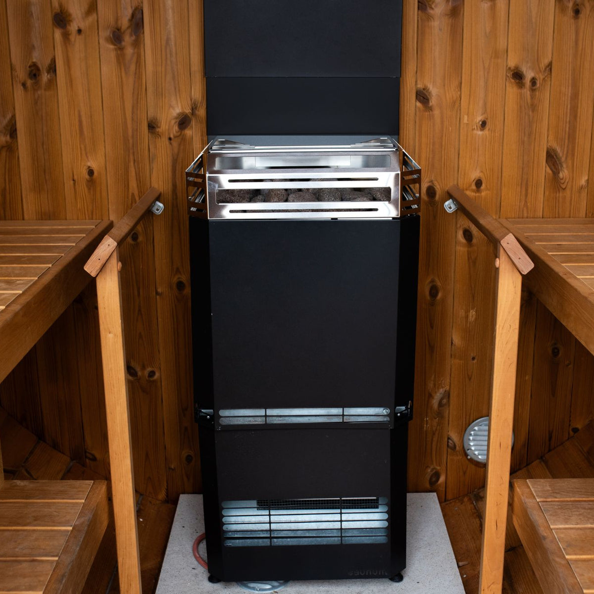 Saunum Air L 10 sauna heater with the closed black steel basket between the benches of a wood sauna