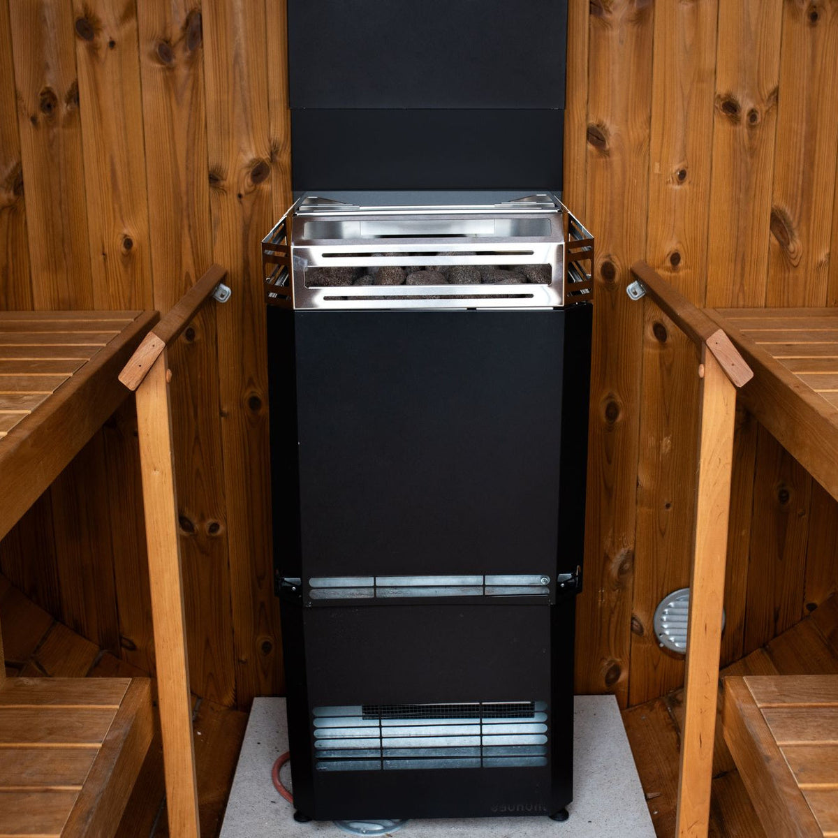 Saunum Air L 13 heater from the package between the benches of a wood sauna
