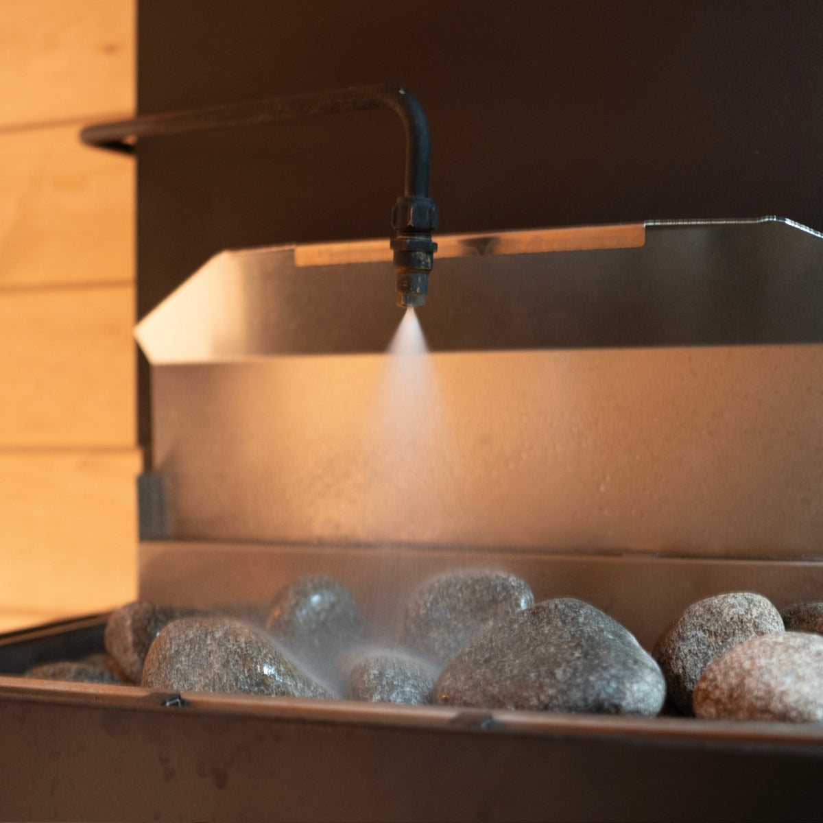 Saunum AutoLeil nozzle misting water over the hot stones of a Saunum heater