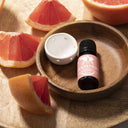 Saunum Grapefruit aroma oil bottle and ceramic aroma cup in a wooden bowl with grapefruit