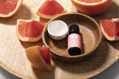 Saunum Grapefruit aroma oil bottle and ceramic aroma cup in a wooden bowl with grapefruit