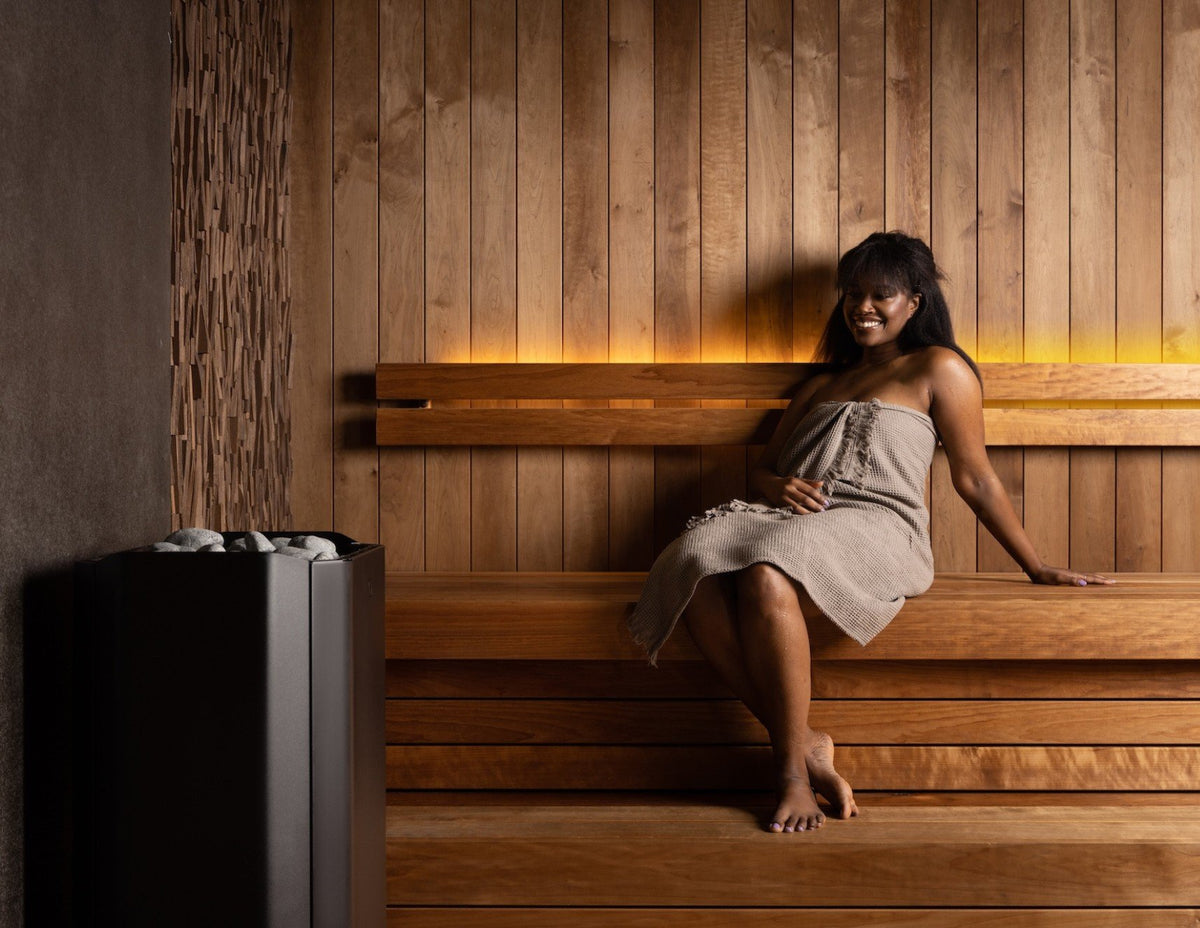 Bather relaxing on a sauna bench beside the Saunum Air Perfect 7 heater