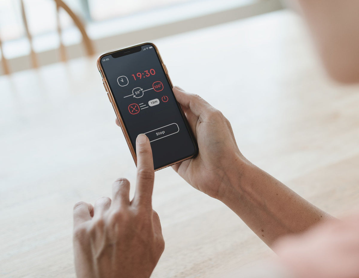 Hands holding a phone running the Saunum AirIQ sauna control app