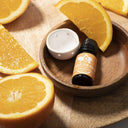 Saunum Sweet Orange aroma oil bottle and ceramic aroma cup in a wooden bowl with orange slices