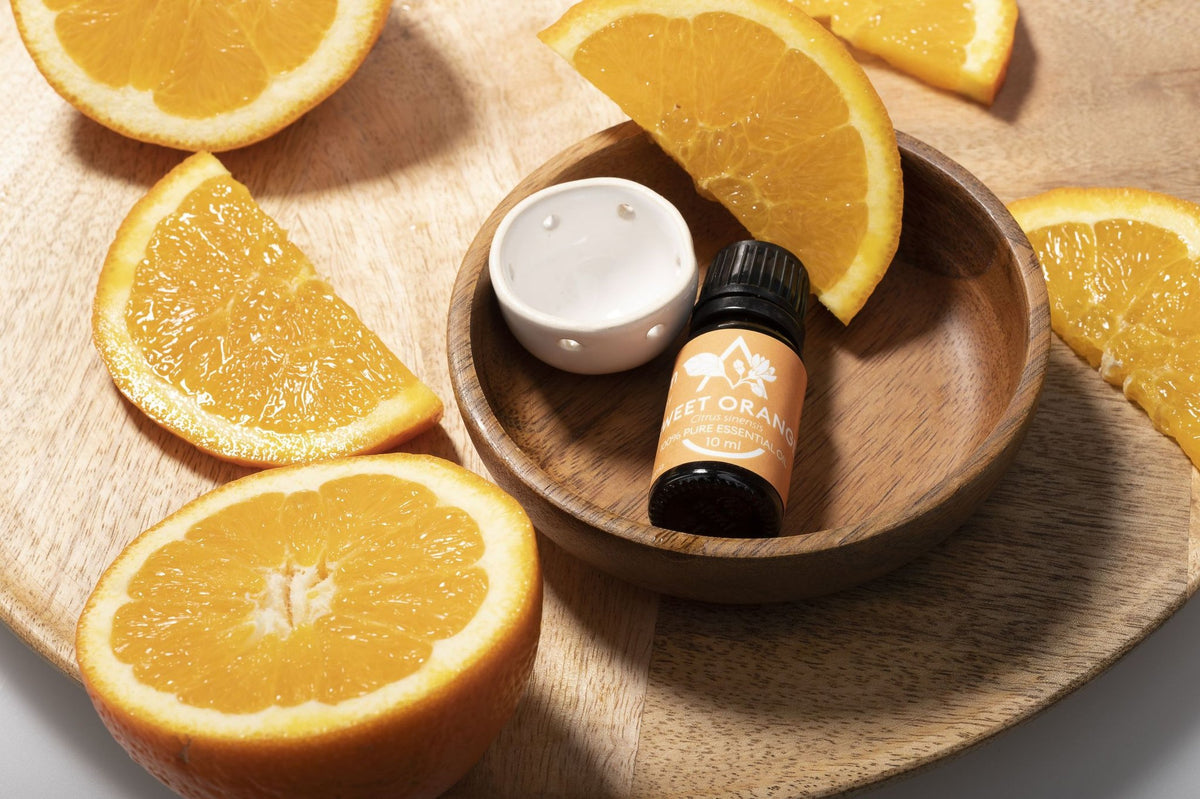 Saunum Sweet Orange aroma oil bottle and ceramic aroma cup in a wooden bowl with orange slices