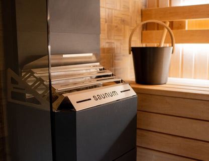 Slatted steel top of the Saunum Air 7 closed basket beside a black sauna bucket