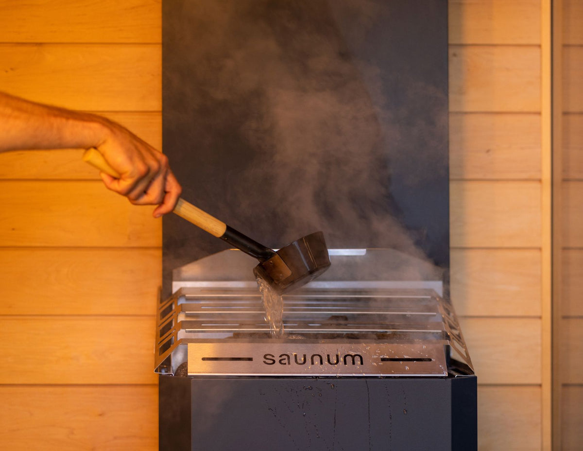 Water ladled over the Saunum Air 5 closed basket top, steam rising
