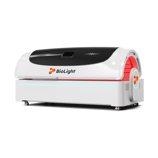 BioLight Apex red light therapy bed closed, white shell with black canopy and red glow at the entry, angled side view