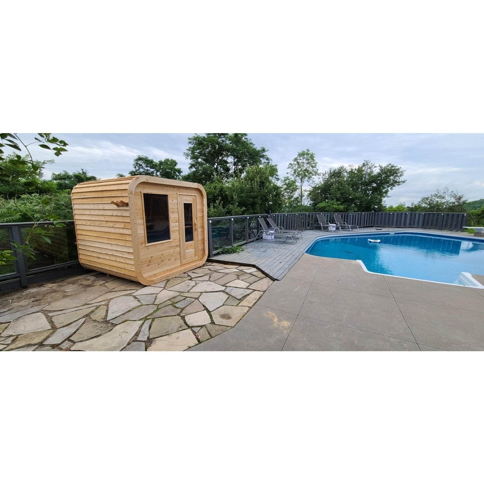 CT Luna sauna on a flagstone patio beside a backyard swimming pool, showing its scale in a finished yard