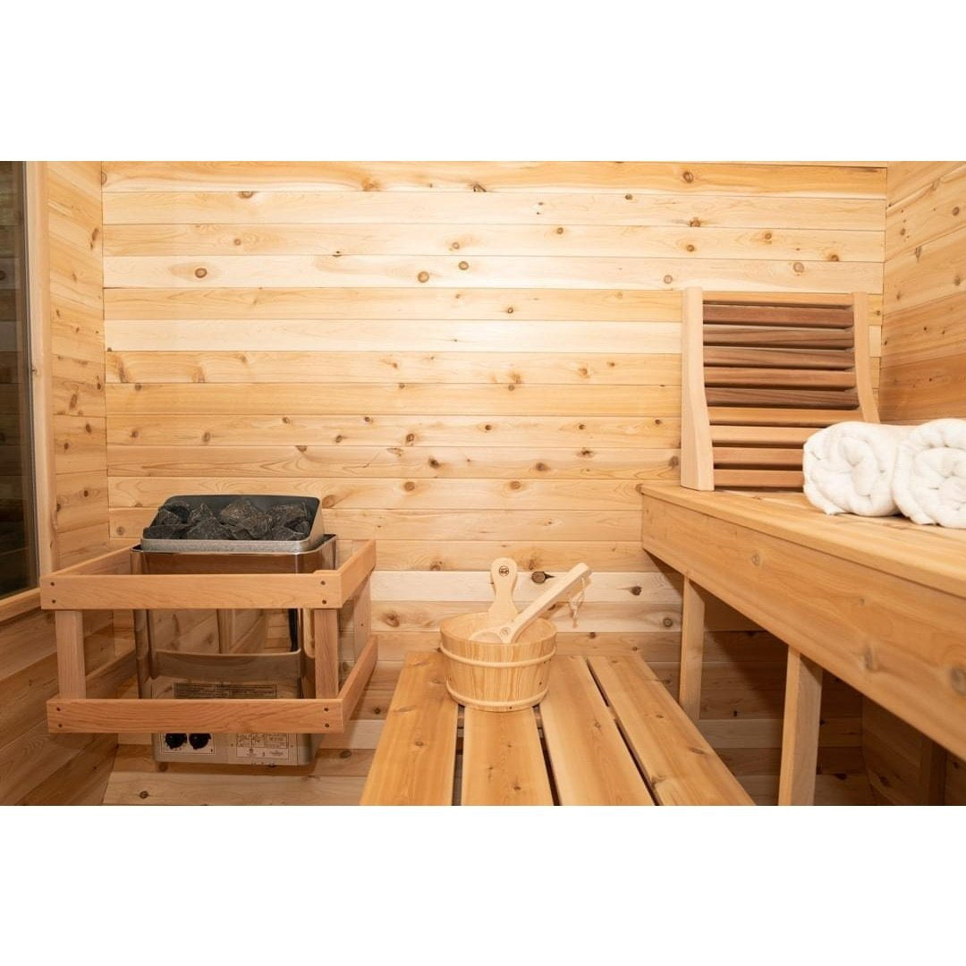 CT Luna electric sauna heater with its stone bed and a cedar bucket and ladle on the bench beside it