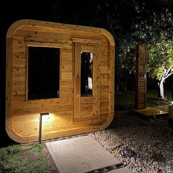 CT Luna sauna lit from within at dusk, showing the glow through the door and window