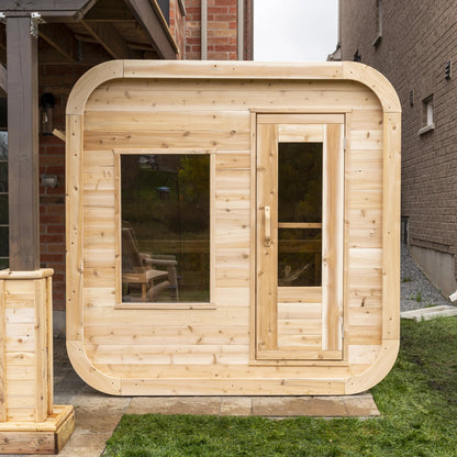 CT Luna outdoor cube sauna installed on a stone patio beside a house, seen from the front
