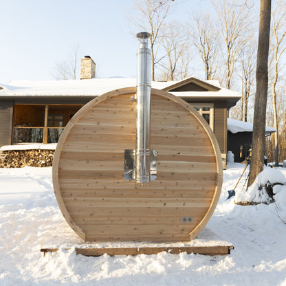 Rear of the wood-fired CT Elation barrel sauna in snow, with the stainless chimney leaving the back wall