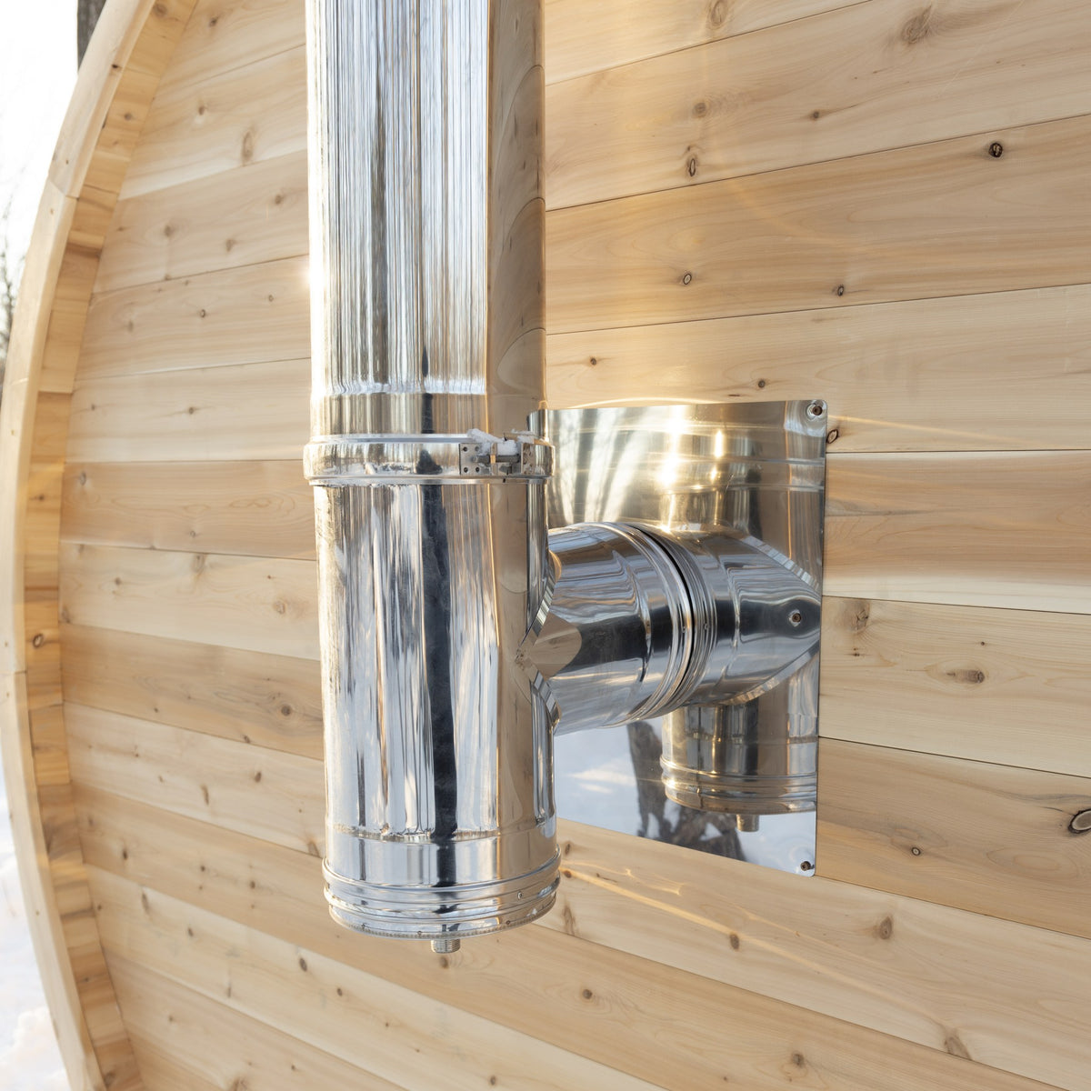 Close view of the stainless chimney pipe and wall thimble where the stove pipe leaves the CT Elation barrel