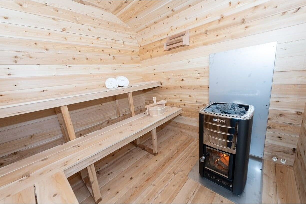 CT Georgian interior with the two-tier cedar benches and a Harvia wood stove behind its heat shield