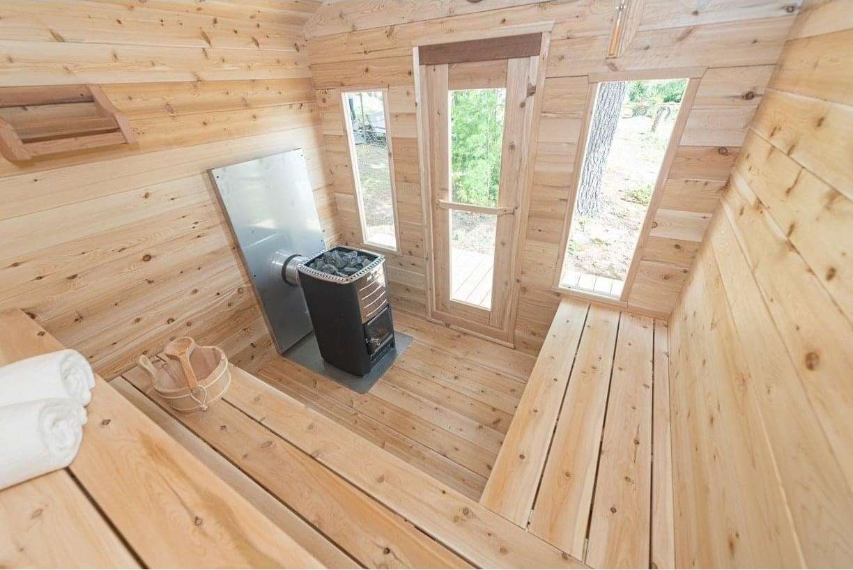 Wide view of the CT Georgian cabin sauna interior with windows, benches and heater