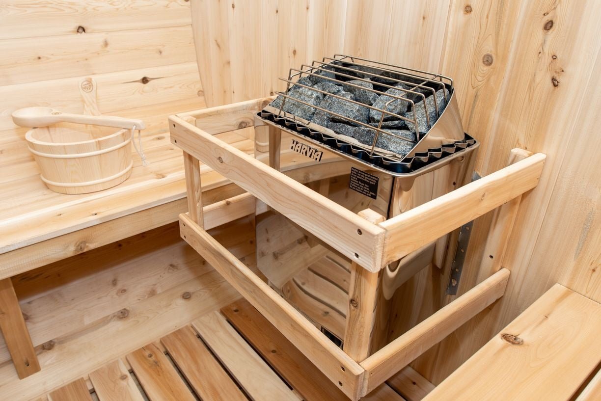 Harvia electric heater inside its cedar guard beside the bench, with bucket and ladle, in the CT Georgian