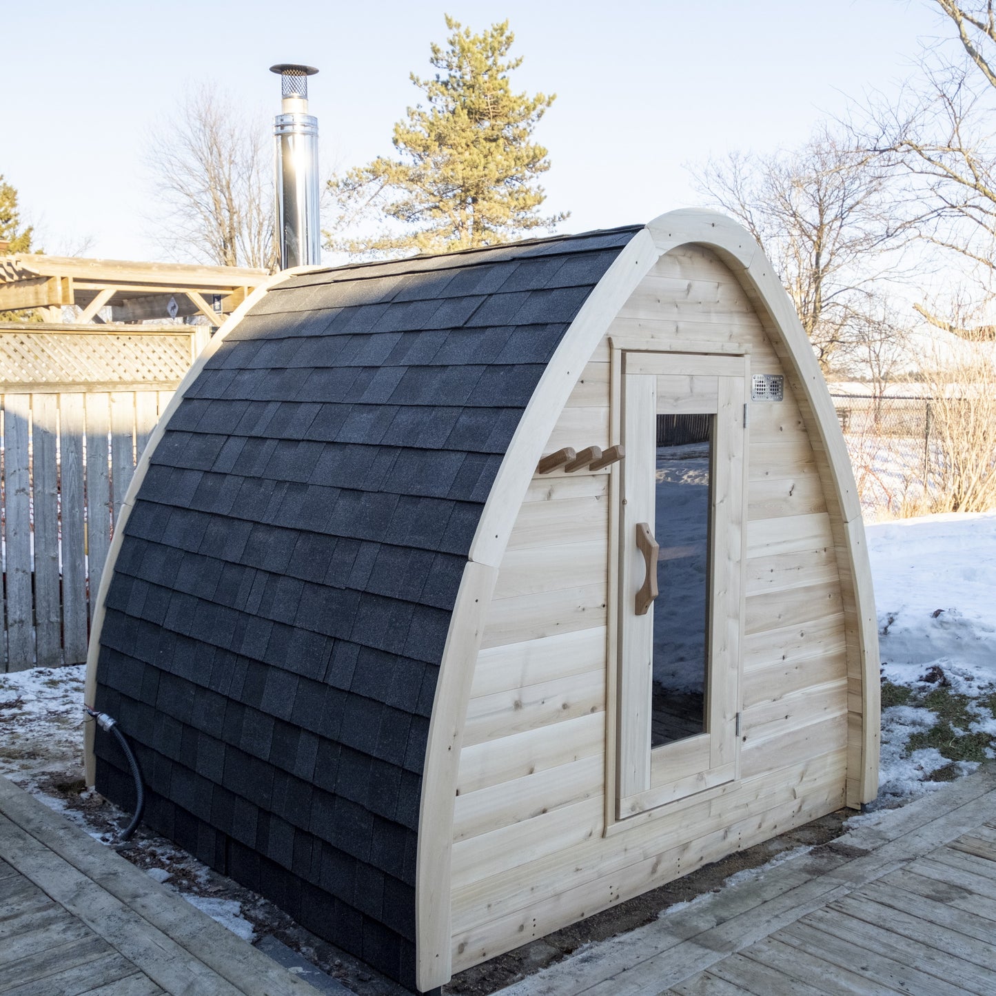 CT MiniPOD sauna three-quarter view from the right showing the door and the black Cambridge shingle roof wrapping the pod