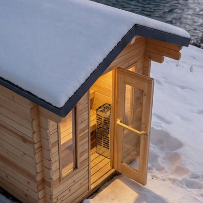 CT Palmer cabin sauna in snow with the door open and the heater visible inside, lake behind