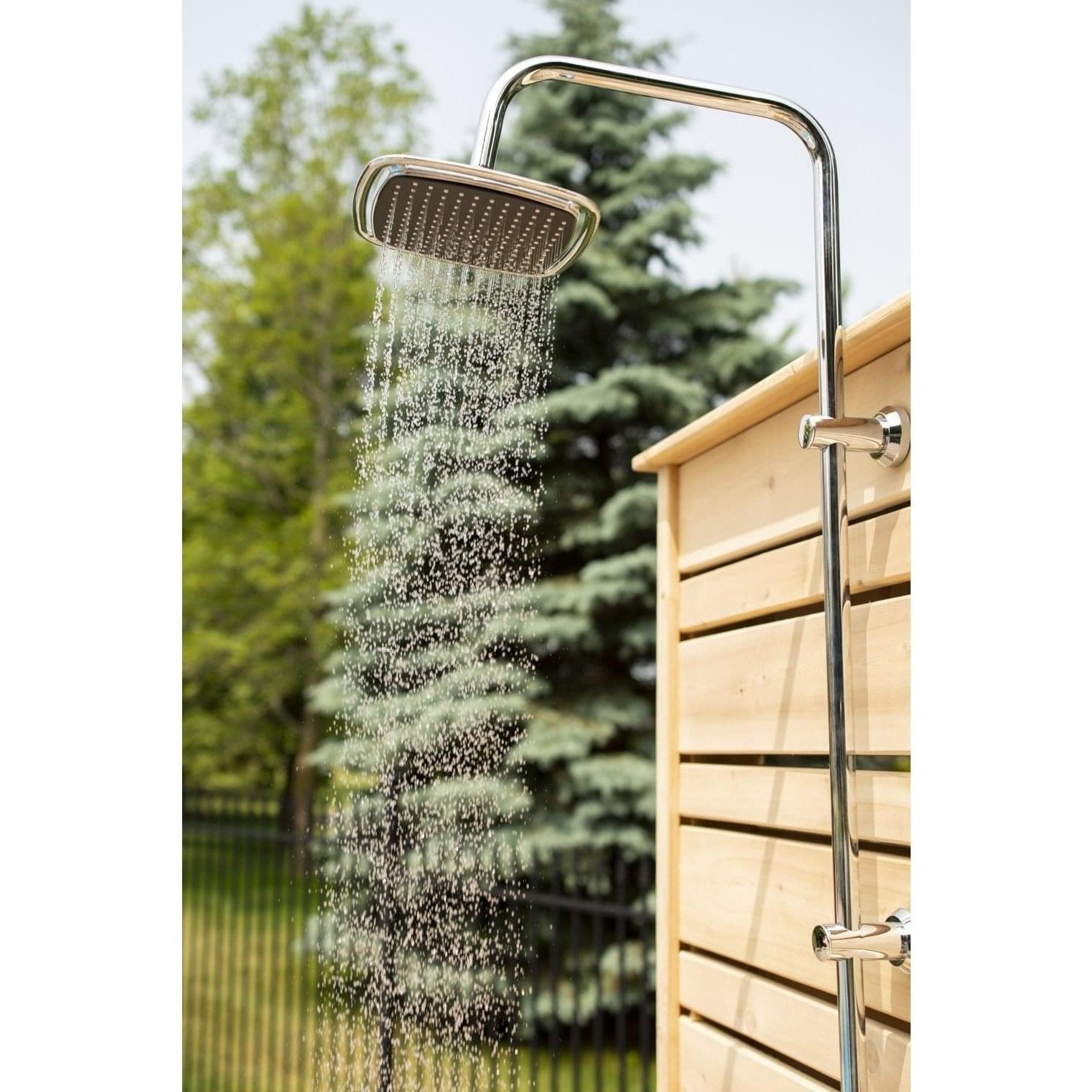 Square chrome rain head spraying beside the top of the Savannah cedar panel, spruce and a black fence behind, head sold separately.