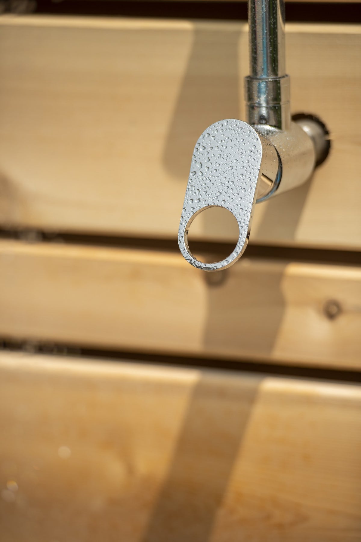Single chrome lever valve beaded with water on the riser, against the horizontal cedar slats of the Savannah panel, sold separately.