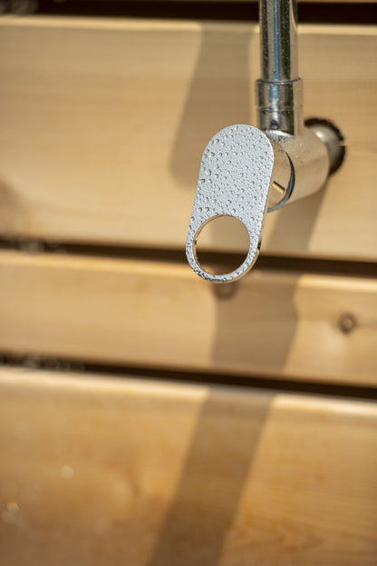 Single chrome lever valve beaded with water on the riser, against the horizontal cedar slats of the Savannah panel, sold separately.
