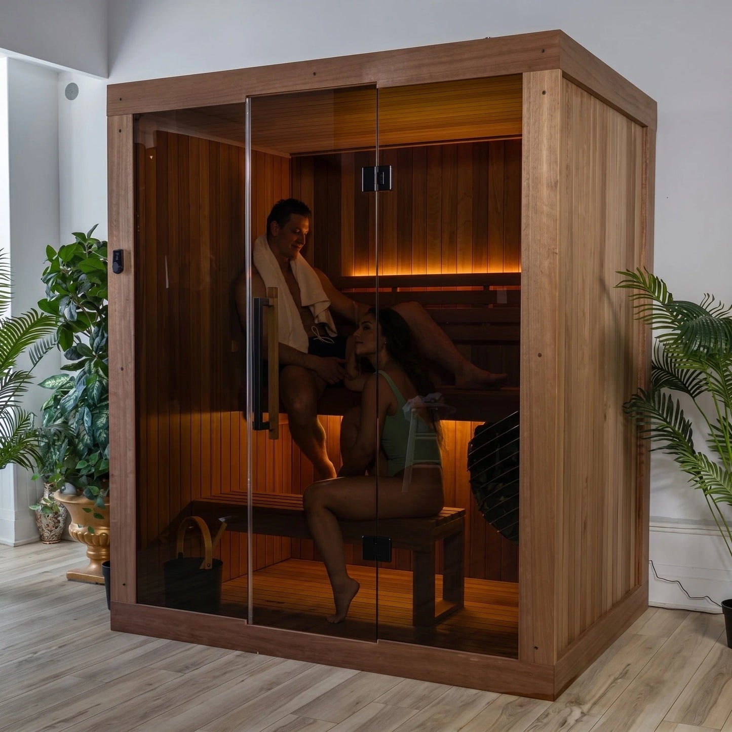 Dundalk LeisureCraft CT Element Loft indoor sauna with two people seated inside, glass front and warm bench lighting