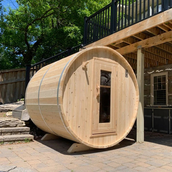 CT Harmony barrel sauna in profile on a paved patio, showing the cedar cradle stands
