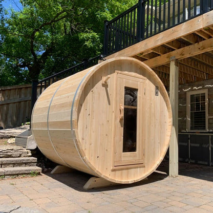 CT Harmony barrel sauna in profile on a paved patio, showing the cedar cradle stands