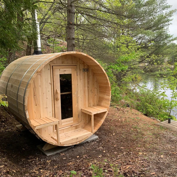 CT Serenity barrel sauna in a wooded lakeside setting with a chimney fitted
