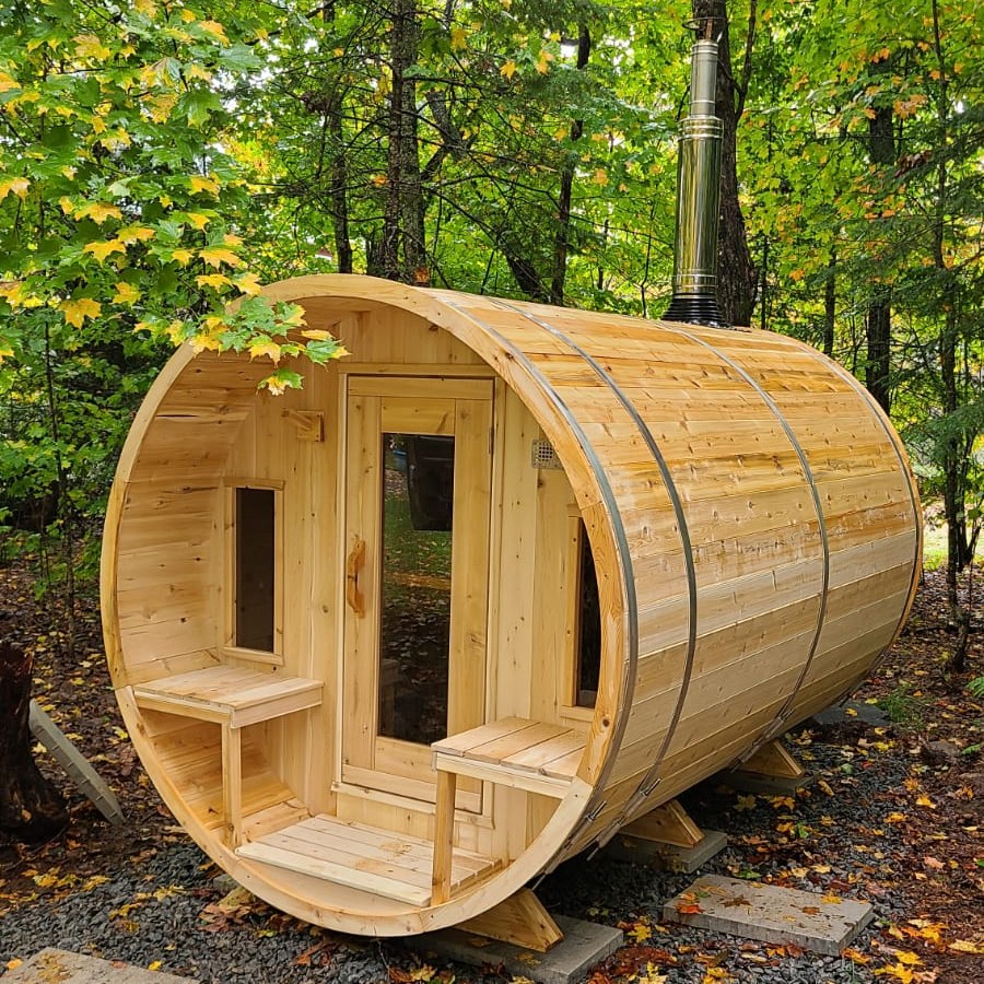 CT Tranquility barrel sauna among autumn trees with a wood-burning chimney fitted