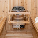 Harvia KIP electric heater recessed between light spruce benches in a sauna, bucket and ladle above