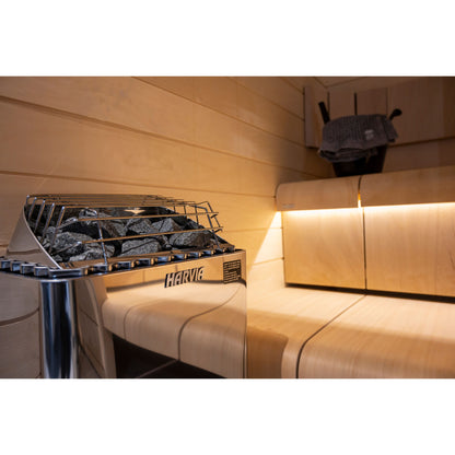 Harvia KIP45B 4.5kW in stainless steel with its stone guard, beside a backlit bench