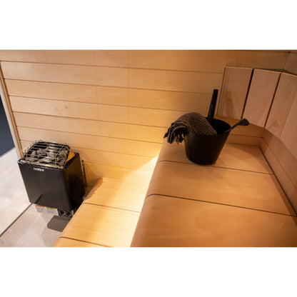 Harvia KIP60B 6kW in graphite black in a sauna corner with a bucket on the bench