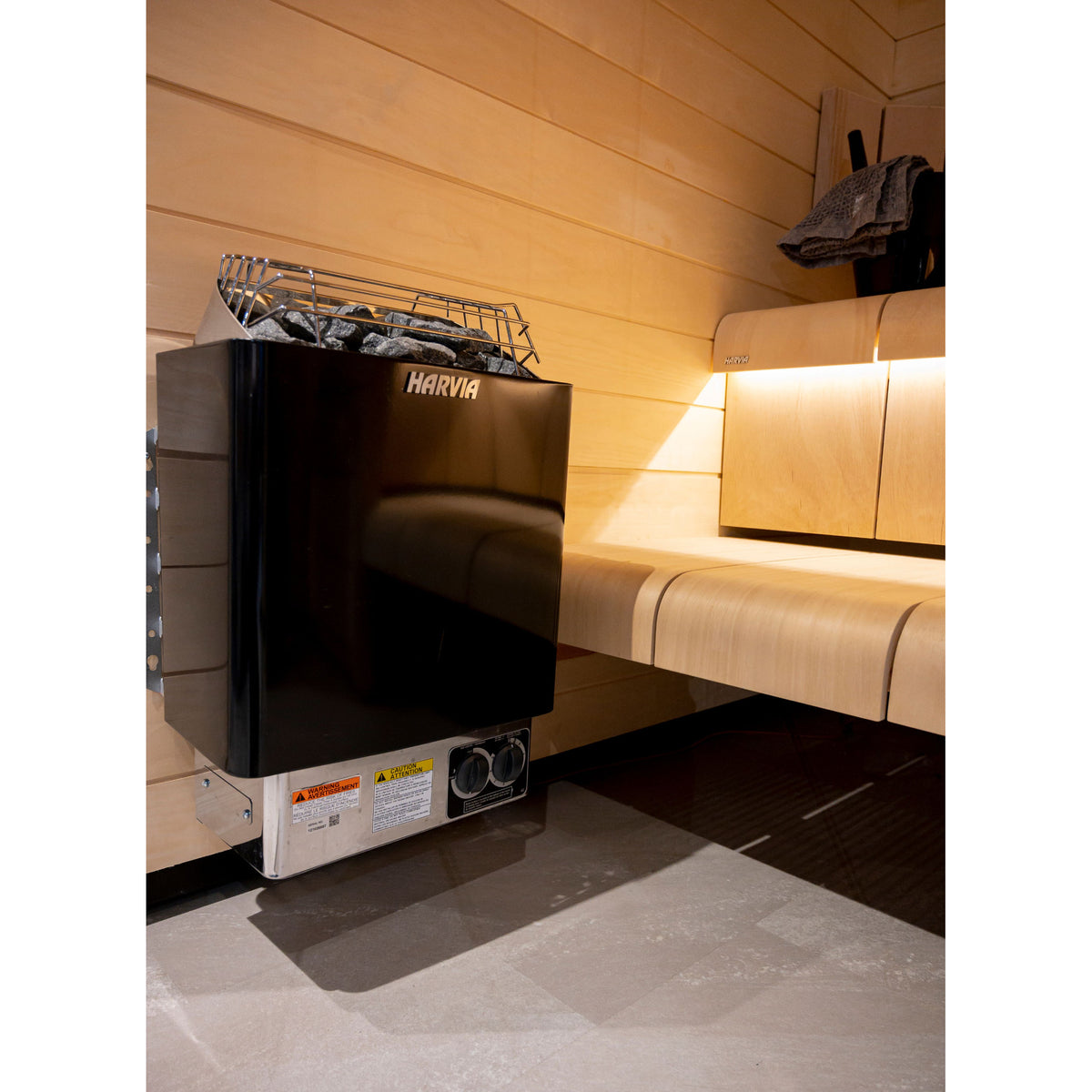 Harvia KIP80B 8kW in graphite black beside a backlit sauna bench