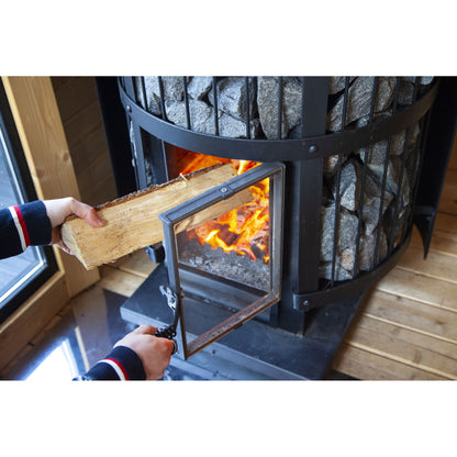 Firewood being loaded into the Harvia Legend 240 Greenflame 15.9kW through its glass door