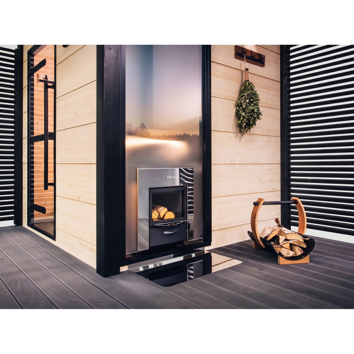 Harvia Pro 36 Duo fire door set into a wall beside a firewood holder, heating the sauna on the other side