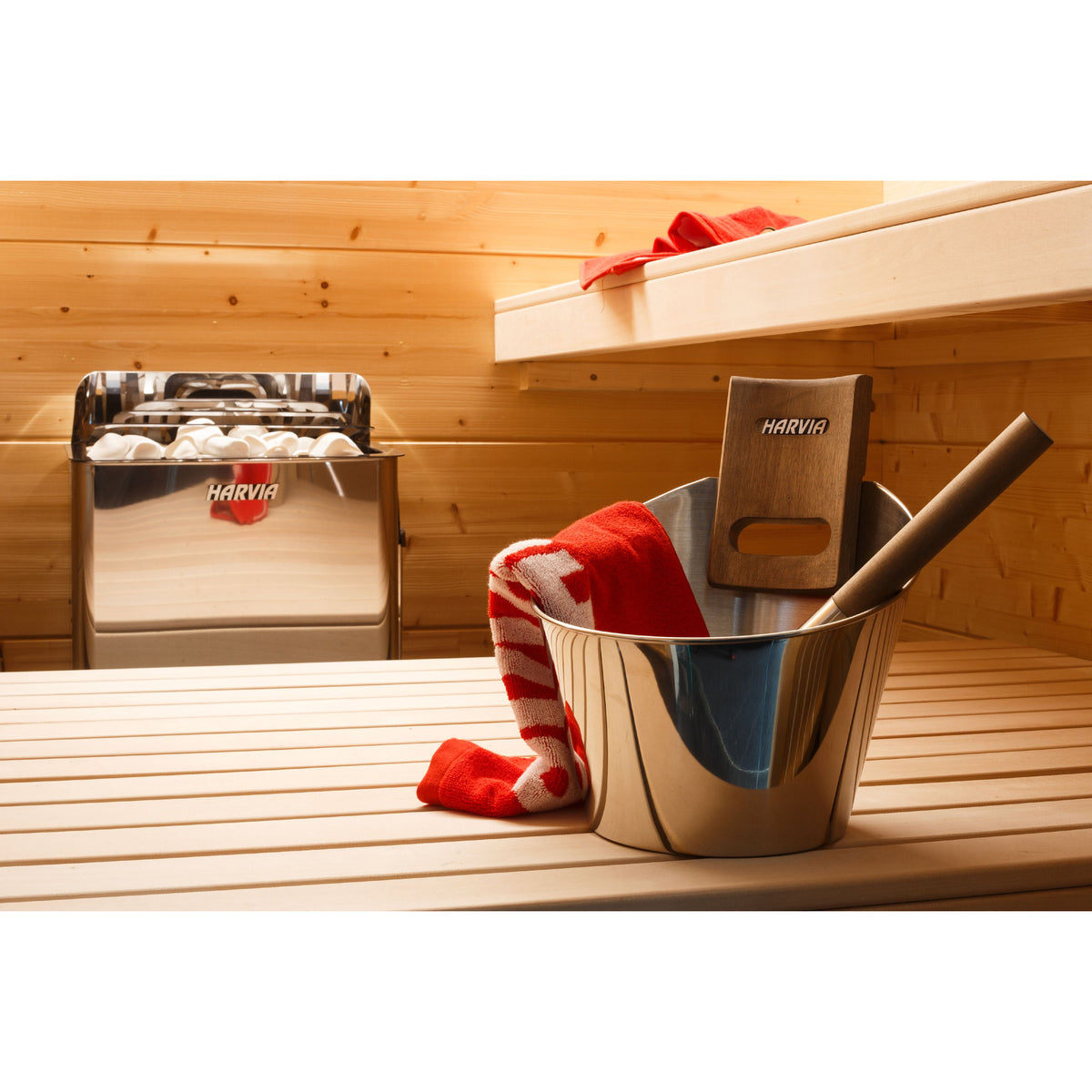 Harvia The Wall SW80 8kW beside the sauna bench with a stainless bucket and red towel