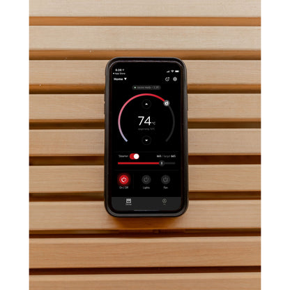 Harvia app on a smartphone showing the sauna temperature dial, against a timber sauna wall