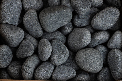 Close up of rounded olivine sauna stones