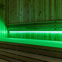 SaunaGlo LED strip lighting in green mode under a cedar sauna bench