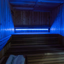 SaunaGlo 72 LED light bar glowing blue under the benches of a cedar sauna