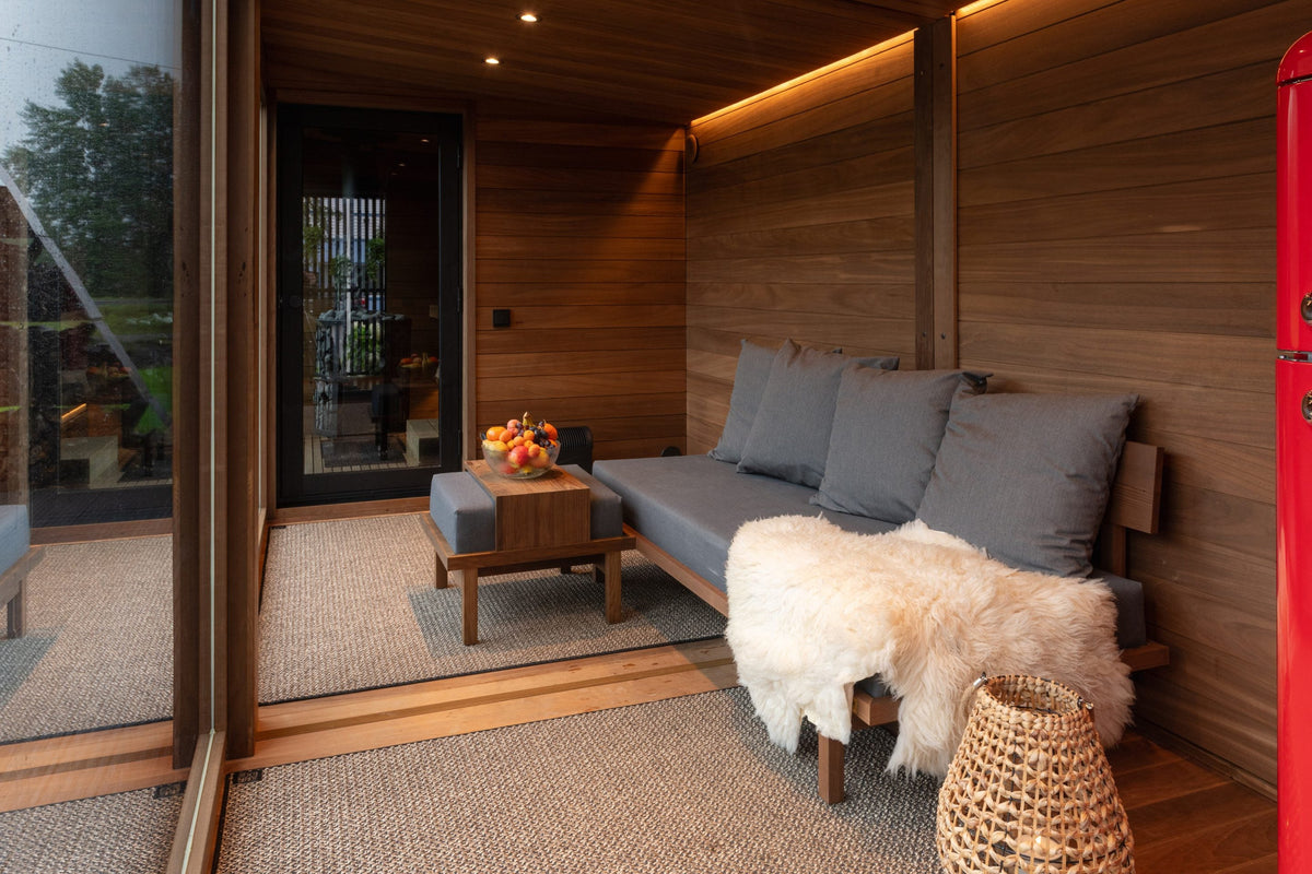 Nordic Misty Lounge interior furnished with a sofa, sheepskin and basket, glazing open to the garden