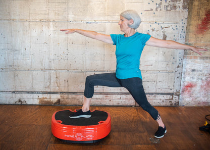 Older woman in a lunge with her front foot on the red Power Plate MOVE