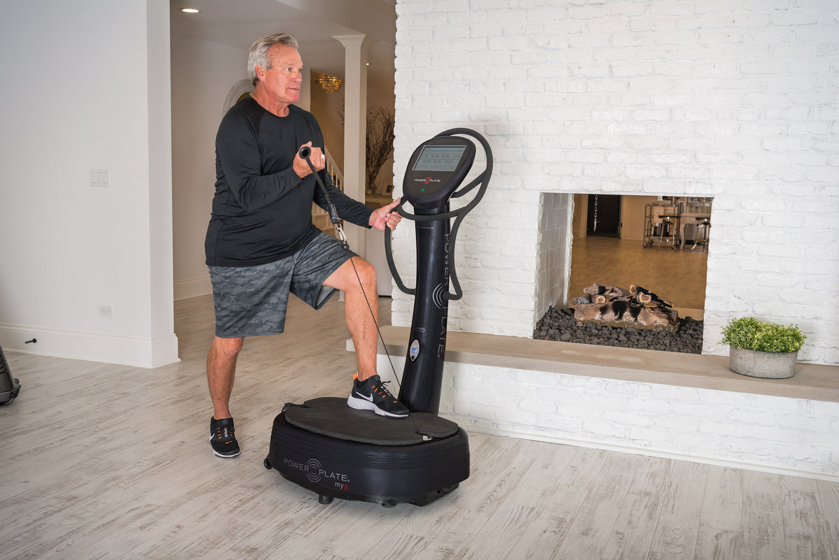 Man in a split squat on the Power Plate my8, pulling one proMOTION cable with his other hand on the handlebar