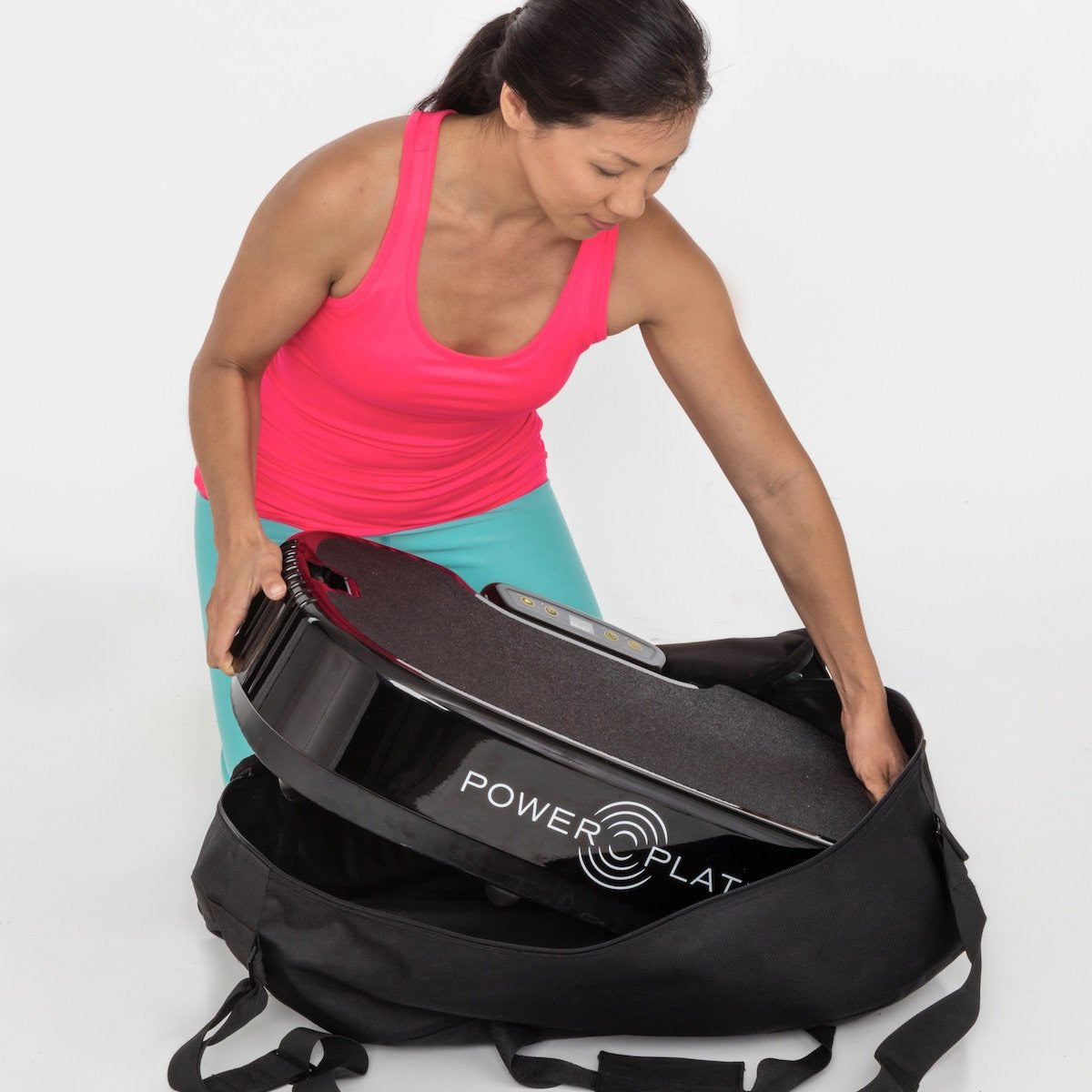 Personal Power Plate being lifted into a soft carrying case, one of the optional case choices for travel