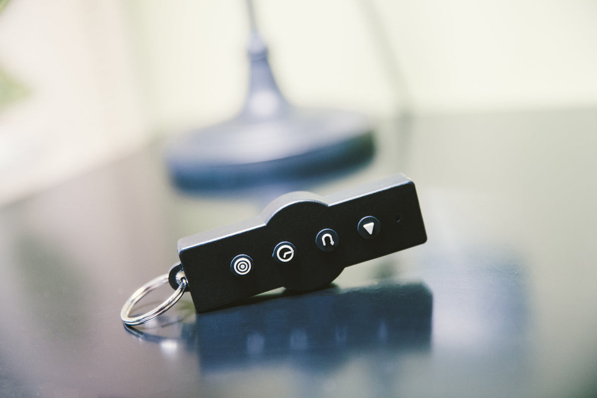 Personal Power Plate remote control on a key ring, resting on a table