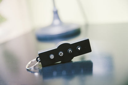 Personal Power Plate remote control on a key ring, resting on a table